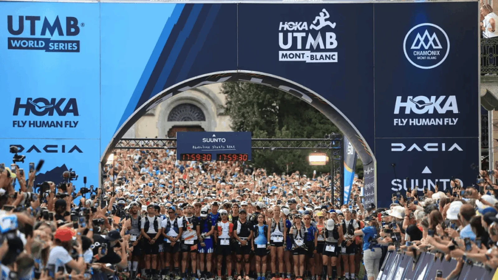 Le peloton massé sous l'arche de départ de l'UTMB à Chamonix, entouré de spectateurs et de photographes